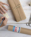 Person wrapping with Straight Up Premium Brown Kraft Paper Roll Hella Thick For Rustic Gift Wrapping And Diy Crafts.