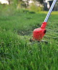 Red electric string trimmer in a garden using 7 Piece Carbide Tipped Grass Trimmer Blades Set For 6 Inch 40 Teeth Replacement Weed Wacker Blades For Electric String Trimmers Metal Cutter Heads For Thick Weeds And Small Branches cutting grass.