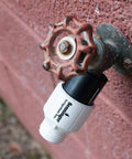 Low-Flow Drip Irrigation Pressure Regulator 25 PSI Three Quarter Inch Hose Thread attached to outdoor faucet on brick wall.