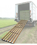 Heavy Duty Gravity Roller Conveyor unloading chute positioned on truck ramp for warehouse use with stainless steel rollers.