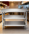 Beefy Stainless Steel Workbench With Three Tier Open Shelving And No Fuss Leveling Feet Built Tough Kitchen Prep Table Or Packing Station For Real Garage Workshop Days with a flat steel top and open shelving.