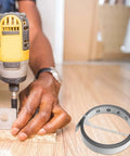 No Fuss Self Adhesive One Meter Steel Metric Track Ruler Tape next to a worker using a drill on wood for precise measurements.
