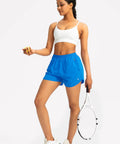Woman posing with racket wearing blue athletic shorts