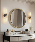 Mermiviok Matte Black Wall Sconces Set of 2, Clear Glass Vanity Lights mounted beside a round mirror in a stylish bathroom.