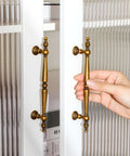 Hand holding super stylish vintage antique brass cabinet pull with 5 inch hole centers on glass door. Get The Look You Want With These