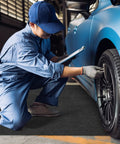 Mechanic inspecting tire over a 4 Pack 36 By 72 Inch Oil Spill Mat For Under Car And Garage Drips Absorbent Pads With Rubber Backing