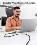 Man using a laptop connected to Snagless Short Shielded Cat6A Ethernet Cables 10Gbps 3Ft Pack Of 5 Black For Ultra Fast LAN Networking.