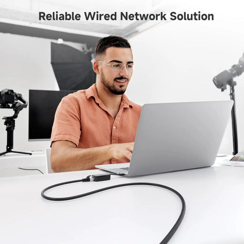 Man using a laptop connected to Snagless Short Shielded Cat6A Ethernet Cables 10Gbps 3Ft Pack Of 5 Black For Ultra Fast LAN Networking.