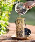 Person refilling Solar Bird Feeder For Outdoors Hanging And Garden Lantern Style Metal Wild Bird Feeder With S Hook Gift For Bird Lovers Heavy Duty Two Pound Capacity Keeps Seed Level Visible And Doubles As Night Light Yard Friendly For Cardinals