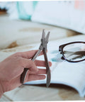 Stainless Steel Eyeglass Repair Pliers Set For Quick Nose Pad Adjustments And No Hassle At Home Fixes DIY Eyewear Maintenance Kit With Pro Grade Tools For Safe Easy Frame Repairs, held in hand with glasses nearby.