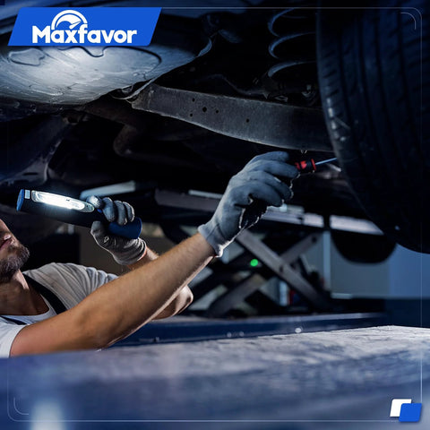 Mechanic inspecting underside of a vehicle with flashlight in a garage