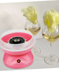 Pink cotton candy machine with cotton candy on wine glasses, featuring Cotton Candy Machine Guard Cover For Sugar Floss Makers Lightweight And Reusable Enclosure Easy To Clean Indoor Use Mess Free Protection That Keeps Little Fingers Safe And Your Countertop Clean.