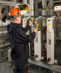 Technician using Pro Grade True RMS Digital Multimeter with Backlit Display and Built-In Temperature Probe in industrial setting.