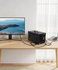 Beefy Thunderbolt 3 External Graphics Dock Paired With 750W Power Supply connected to a laptop and monitor on a wooden desk.