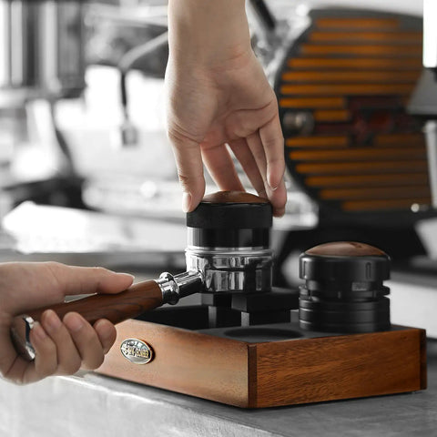 Close-up of hands using 58mm Espresso Coffee Distributor Leveler With Stepless Height Adjustment at a cafe, stainless steel, black finish