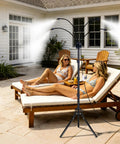 Outdoor Patio Misting System With Adjustable Five Point Seven Five Foot Spray Stand Twenty Six Point Five Foot Water Supply Line Portable Outdoor Mister For Cooling On Patios Yards BBQs Pools Beaches And Tanning with two women lounging on patio chairs
