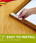 Hand applying Heavy Duty Picture Hanging Strips XL 20Lb Capacity 10 Pairs 20 Strips Damage Free Hangers for Picture Frames.