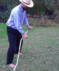 Man using Curved Metal Scythe Blade And Snath With A 53 Inch Handle 22 And A Half Inch Long Blade By 2 And A Quarter Inch Wide Reinforced Spine Made In USA Handcrafted For Light Brush Clearing Grass And Grain Work on grass field