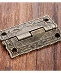 Close-up of an Antique Bronze Cabinet Hinge for Jewelry Boxes and Small Furniture, 35x23mm, decorative and vintage style, on wood surface.