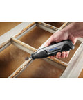 User holding an Ultra Compact Four Volt Cordless Rotary Tool Featuring Variable Speed And No Sweat Accessory Swaps for sanding trim.