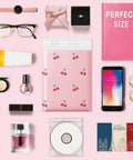 Pink Bubble Mailers 6x10 Inch 100 Pack Waterproof Self Seal Padded Envelopes for Shipping, surrounded by various small items.