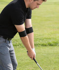 Man using Swing Correcting Arm Band 4 Pack Elastic Golf Swing Trainer For Right And Left Handed Players No Chicken Wing Aid on golf course.