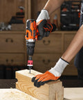 Side view of orange and black cordless drill with pink depth-stop countersink bit drilling into a wooden block.