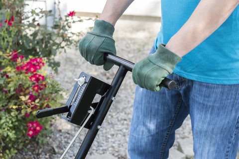 Person using Pro Push Broadcast Spreader 85 Lb Capacity with Durable Plastic Hopper in a garden setting