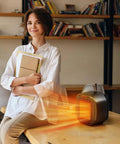 Portable Ceramic Space Heater 1200W With 3 Modes on desk, woman holding books, indoor office setting, compact and safe black heater