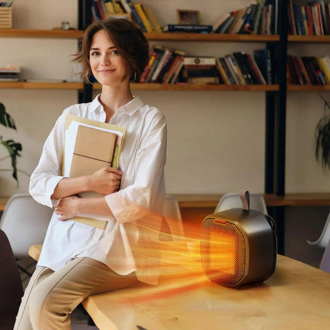 Portable Ceramic Space Heater 1200W With 3 Modes on desk, woman holding books, indoor office setting, compact and safe black heater