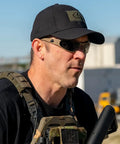 Heavy Hit Ballistic Safety Sunglasses Featuring Milspec Impact Resistant Wrap Frame And Ansi Certification worn by man in tactical gear outdoors.