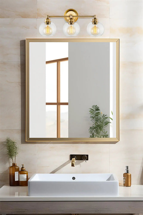 22 Inch Modern Three Light Vanity Bathroom Light With Clear Glass Globe Shades And Warm Brass Finish above bathroom mirror