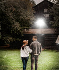 Couple walking under Hella Bright Outdoor LED Stadium Light 300W 42000 Lm 6500K IP67 illuminating a barn at night.
