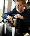 Person on a train packing a TSA Friendly Carry On Travel Backpack for Men and Women With 180 Degree Full Opening Waterproof Pocket.