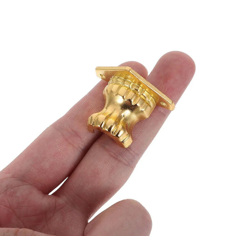 Antique Metal Box Feet Corner Protectors Set Of 20 for jewelry boxes held in hand, showcasing golden metallic finish and detailing.
