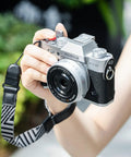 Person holding camera with XT30III Pro Thumb Grip With Shutter Button For XT30II XT20 XT10 Mirrorless Cameras Metal Thumb Rest, outdoors.