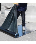 Person unrolling Heavy Duty Roof Underlayment Roll With Ice And Water Shield for outdoor use on a roof.