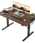Klicelor 48 x 28 Electric Standing Desk With Memory Presets And Hooks Height Adjustable Sit Stand Up Home Office Computer Table with dual monitors and laptop on dark walnut finish.