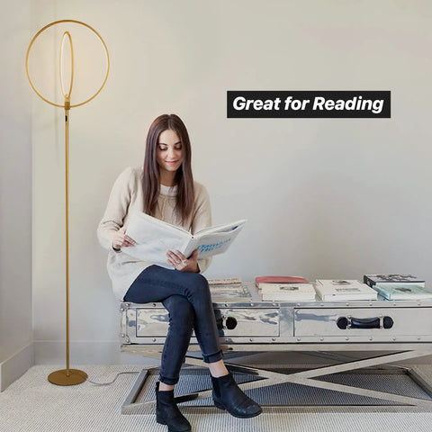 Woman reading next to Eclipse Dope Bright Modern LED Torchiere Floor Lamp With Built In Touch Dimmer, gold finish.