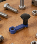 Two Pack Hand Crank Rotary Tiller Lift Handle with black knob on wooden surface surrounded by bolts.