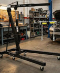 Bad Boy Heavy Duty Folding Hydraulic Engine Hoist And Cherry Picker Rock Solid Shop Crane crushing loads in a garage workshop.