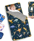 Child lying in Cozy Toddler Nap Mat With Pillow All In One Thickened Extra Large Sleeping Bag For Travel Daycare Naps Plush Minky Dot Lining And Ultra Soft Comfort Everyday, dinosaur print, rolled-up mat shown.