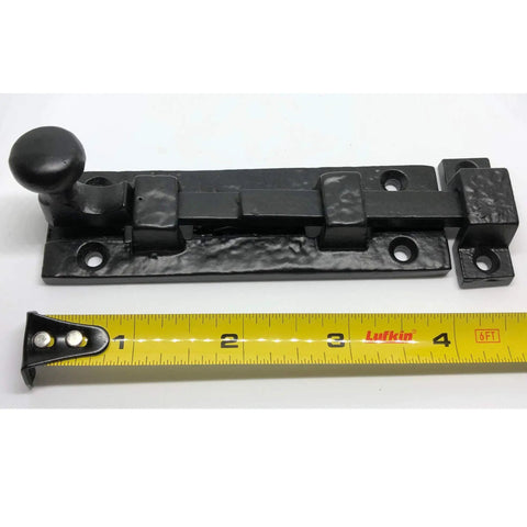 Rock Solid Heavy Duty Cast Iron Sliding Door Bolt Latch 5 Inch close-up with yellow tape measure, rustic farmhouse style