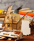 Front view of basswood craft house model kit components and tools on a workbench