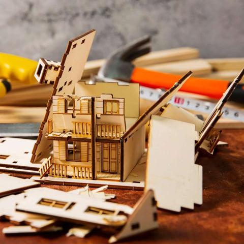Front view of basswood craft house model kit components and tools on a workbench