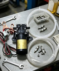 Powerful 12V Self-Priming Oil Transfer Pump For Quick Car And Truck Fluid Extraction At Home Or Shop With Heavy Duty Build with hoses and clamps.
