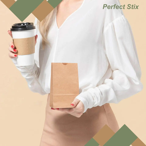 Person holding a coffee cup and a 2Lb Brown Paper Bags Pack Of 500 For Snacks Desserts And Small Dishes Takeout Durable 2 Pound Capacity Eco Friendly Recyclable Bag