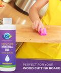 Food Grade Mineral Oil For Cutting Boards And Wood Surfaces Restore And Protect Cutting Boards Butcher Blocks Countertops And Steel Surfaces With Non GMO Vegan Gluten Free USP Approved Low Viscosity For Maximum Wood Absorption bottle next to a person cleaning a wooden cutting board with a pink cloth