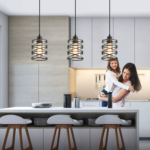 Killer Three Pack Pendant Lights For Kitchen Island And Dining Table Matte Black Spiral Cage With Clear Glass Shades hanging over a modern kitchen island.