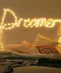 Battery Operated Fairy String Lights 10 Feet With 30 Warm White LEDs arranged to spell 'Dreamer' above a cozy bed setup